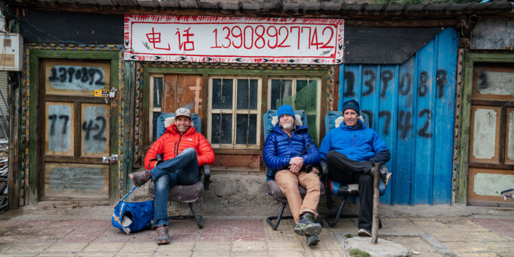 Jim Hurst, Thom Pollard, and Mark Synnott sit in Jilong shortly after crossing the border from Nepal. (National Geographic/Renan Ozturk)